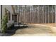 View of the backyard, including the side entrance to the home, landscaping, and towering pine trees at 7440 Summer Tanager Trl, Raleigh, NC 27614