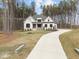 An elegant cream-colored house features a long, curved driveway and meticulously maintained landscaping in a wooded location at 7440 Summer Tanager Trl, Raleigh, NC 27614