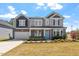 Beautiful two-story home with stone accents, a covered front porch, attached garage, and manicured lawn at 541 Henham Way, Zebulon, NC 27597