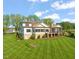 Back exterior view with manicured lawn, screened in porch, balcony, and stone foundation at 1641 Legacy Ridge Ln, Wake Forest, NC 27587
