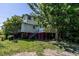 A mostly cleared backyard with gravel and green grass with thick trees and shrubbery at the rear of the property at 527 S East St, Raleigh, NC 27601