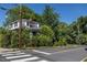 Exterior of a white home with dark shutters, surrounded by mature trees and bushes, viewed from the street at 527 S East St, Raleigh, NC 27601