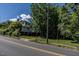 A white home with a brick foundation and green grass is partially obscured by trees on a sunny day at 527 S East St, Raleigh, NC 27601