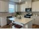 Bright kitchen features white cabinetry, stainless appliances, and a central island with seating for casual dining at 115 Shooting Star Trl, Youngsville, NC 27596