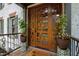 Close-up of a custom wood front door with decorative glass panels and potted plants enhancing the entryway at 1800 Bay Meadow Ct, Raleigh, NC 27615