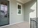 Charming covered porch with gray siding, white trim and a gray front door and black iron railing at 205 Wash Hollow Dr, Wendell, NC 27591