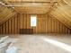 Spacious unfinished attic with wood framing and window, offering potential for customization at 205 Wash Hollow Dr, Wendell, NC 27591