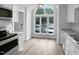 Eat-in kitchen features white cabinets, granite countertops, stainless steel appliances, and a large arched window at 1432 Quarter Pt, Raleigh, NC 27615
