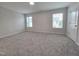 Spacious bedroom with neutral walls, carpet, two windows, and a white door at 3006 Freewinds Way # 41, Cary, NC 27519