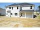 The back exterior of this two-story home featuring white siding and black roof, along with a covered lanai at 136 Newport Lndg, Garner, NC 27529