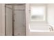 Bright bathroom featuring a tiled shower, soaking tub, and frosted privacy window at 136 Newport Lndg, Garner, NC 27529