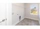 A bright laundry room with gray tile flooring, a window, and a wire shelving unit above the hookups at 136 Newport Lndg, Garner, NC 27529