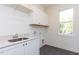 Bright laundry room with white cabinets, quartz countertops, and a window for natural light at 162 Gaines Trail, Pittsboro, NC 27312