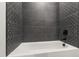Modern bathroom with decorative dark grey tiled walls and a sleek tub at 5812 Shawood Dr, Raleigh, NC 27609
