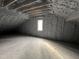 View of a house attic showcasing insulation behind a window at 5208 Knollwood Rd, Raleigh, NC 27609