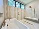 Modern bathroom featuring a soaking tub, shower with a bench, neutral tiles, and gold fixtures at 5208 Knollwood Rd, Raleigh, NC 27609