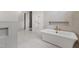 Bright bathroom featuring a soaking tub with gold fixtures, heated towel rack and white tiled floors at 5208 Knollwood Rd, Raleigh, NC 27609