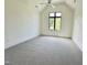 Spacious and brightly lit empty bedroom with a gray carpet and a view of the surrounding neighborhood at 5208 Knollwood Rd, Raleigh, NC 27609