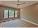 Bright bedroom featuring a ceiling fan and a large window with views of the outdoor scenery at 5208 Knollwood Rd, Raleigh, NC 27609