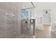 Bright bathroom featuring glass shower with a window, tile walls, and hardwood floors leading to the bedroom at 55 Harvest View Way, Franklinton, NC 27525