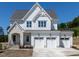 Two-story white home boasts a three-car garage, manicured lawn, and elegant architectural details at 6048 Scalybark Rd, Durham, NC 27712