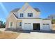 Striking two-story home showcasing a light brick entryway, multiple garage, and white siding at 6048 Scalybark Rd, Durham, NC 27712