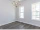 Bright, open room with hardwood floors, two windows, and a modern chandelier at 6048 Scalybark Rd, Durham, NC 27712