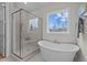 Bright bathroom featuring a glass shower and a luxurious soaking tub by a sunlit window at 820 Willow Tower Ct # 153, Rolesville, NC 27571