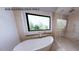 Modern bathroom featuring a standalone tub, glass-enclosed shower, and a large window providing ample natural light and serene views at 4123 Rockingham Dr, Raleigh, NC 27609