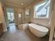 Modern bathroom with a soaking tub, glass shower, and neutral tile at 165 Inspiration Way, Fuquay Varina, NC 27526