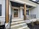 Inviting home entrance with stone steps and stylish front door, featuring wood columns and black railing at 165 Inspiration Way, Fuquay Varina, NC 27526