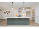 Bright kitchen featuring a large island with a sink, white cabinets, and modern lighting fixtures at 35 Uptown Rd, Zebulon, NC 27597