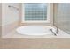 A relaxing tub is surrounded by tile and features a glass block window for natural light at 6366 Lineberry Rd, Liberty, NC 27298
