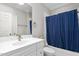 Well-lit bathroom featuring a tub with blue shower curtain and white vanity at 6366 Lineberry Rd, Liberty, NC 27298