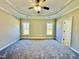 Large main bedroom featuring a tray ceiling, ceiling fan, neutral carpet, and natural light at 144 Emerson Fields Dr, Pikeville, NC 27863