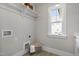 Neutral laundry room with tiled floor, white trim, hanging rack, and window with natural light at 210 Colvard Farms Rd, Durham, NC 27713
