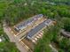 Aerial view of a neighborhood featuring townhouses with black roofs surrounded by lush green trees at 6402 Tanner Oak Ln, Raleigh, NC 27613