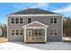 Back of a gray home with a covered patio and multiple windows, set against a snowy ground and sky at 130 Bold Dr, Youngsville, NC 27596