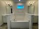 Bathroom featuring a soaking tub with white tile accents and dual sinks with mirrors at 168 Grand Griffon Way, Lillington, NC 27546
