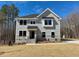 Two-story home with light gray siding, stone accents, black trim, and a manicured lawn on a sunny day at 168 Grand Griffon Way, Lillington, NC 27546