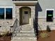 Close-up of the front door with stone surround and a black iron handrail, leading to the entrance at 168 Grand Griffon Way, Lillington, NC 27546