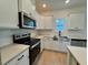 Well-lit kitchen featuring stainless appliances, quartz counters and a farmhouse sink at 168 Grand Griffon Way, Lillington, NC 27546