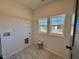 Bright laundry room features tile flooring, two windows, and connections for washer and dryer at 168 Grand Griffon Way, Lillington, NC 27546