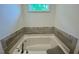 Bathroom featuring a soaking tub with a tile surround and a window at 196 Grand Griffon Way, Lillington, NC 27546