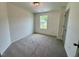 Bright bedroom featuring carpet flooring, white walls, a window and a gray door at 196 Grand Griffon Way, Lillington, NC 27546