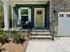 Charming front entrance with stone steps, black railings, and a vibrant yellow door, surrounded by manicured landscaping at 196 Grand Griffon Way, Lillington, NC 27546
