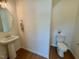 Stylish half-bathroom featuring a pedestal sink, hardwood floors, and a neutral color palette at 196 Grand Griffon Way, Lillington, NC 27546