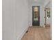 Hallway featuring hardwood floors, white walls and grey door at 414 S Cross St, Youngsville, NC 27596