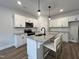 Modern kitchen boasts white cabinets, granite countertops, and a stylish island with pendant lighting at 152 S Mistflower St, Clayton, NC 27520