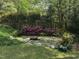 A backyard featuring stone patio and landscaping, including blooming azaleas, offers a serene outdoor living space at 184 Pine E St, Lillington, NC 27546